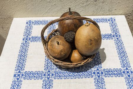 Still life with fruits in wooden basket on table covered with white cloth with blue tracery.の写真素材
