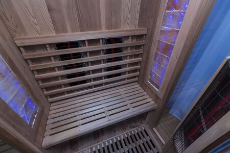Infrared sauna interior close up view. Wooden walls and bench, ceramic heaters. Healthy lifestyle concept.の写真素材