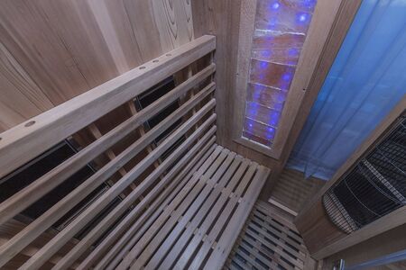 Infrared sauna interior close up view. Wooden walls and bench, ceramic heaters. Healthy lifestyle concept.の写真素材