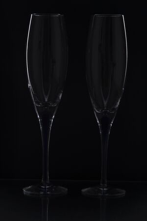 Close up view of contour of a beautiful two slim, tall and elegant champagne glasses isolated on a black background. Beautiful background.の写真素材