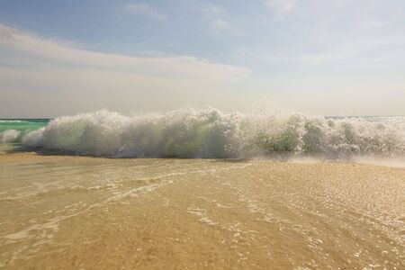 Big wave in Caribbean sea is breaking the coast. Eagle Beach of Aruba Island. Beautiful nature background.の写真素材