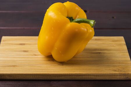 Close up view of yellow pepper with water drops isolated on wooden background. Beautiful nature backgrounds.の写真素材