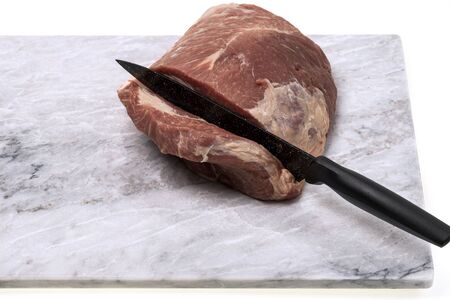 Close up view of raw pork meat with knife isolated on marble cutting board. Food concept.の写真素材