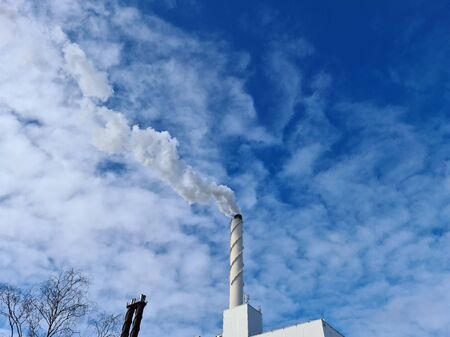 View of white smoke from chimney on blue sky background. Ecology and greenhouse effect concept.の写真素材