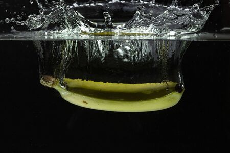 Close up view of colorful banana falling in water on black background. Gorgeous backgrounds.の写真素材