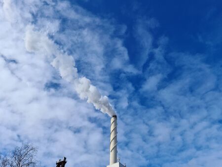 View of white smoke from chimney on blue sky background. Ecology and greenhouse effect concept.の写真素材