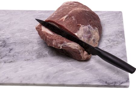 Close up view of raw pork meat with knife isolated on marble cutting board. Food concept.の写真素材