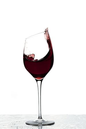 Close up view of splashing red wine in glass isolated on white background.の写真素材