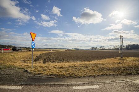 Beautiful nature landscape view on sunny spring day. Roundabout sign on yellow field and blue sky with white clouds background.の写真素材