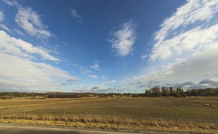Beautiful landscape view with fields, forest trees and blue sky with white clouds. Gorgeous spring backgrounds. Swedenの写真素材