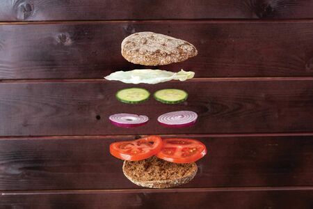 Close up view of homemade sandwich with flying ingredients on wooden background.の写真素材