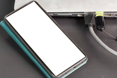 Close up view of connecting usb cable mobile phone with mockup image blank screens and usb flash...