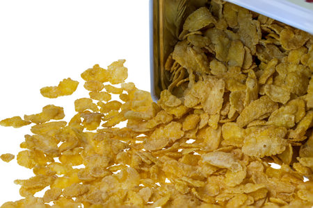 Close up view of fallen metal jar with cornflakes on white background. Healthy food concept.