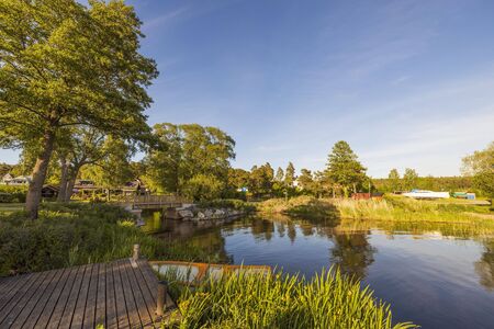 Beautiful nature landscape view of lake and motor boat parked on coast. Green trees and plants on blue sky with white clouds background. Sweden Europeの写真素材