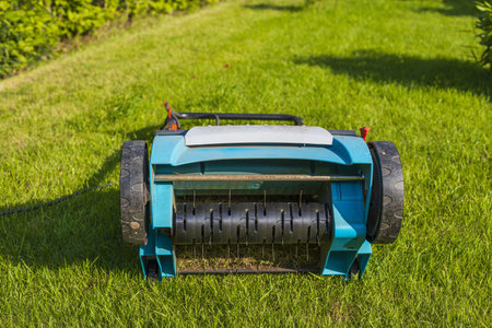 Close up view of electric lawn aerator on green grass isolated. Garden machines concept.