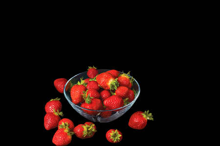 Close up view of fresh red strawberry in glass bowl on blackbackground. Healthy food concept.の写真素材