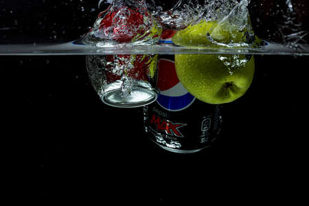 Close up view of green apple, coca and pepsi falling in water on black background. Gorgeous backgrounds. 10.19.2020. Uppsala. Sweden.のeditorial素材