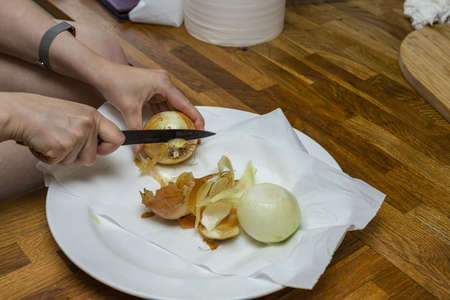 Close up view of female hands peeling onions. Cooking concept.の写真素材
