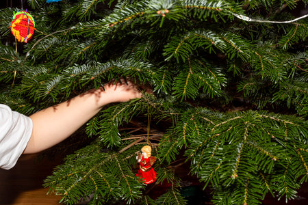 Close up view of child hand beginning decorate christmas tree with angel figure.の写真素材