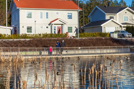 Beautiful spring landscape view. Family with child walking near local pond. Another family leaving their home for walking. Uppsala. Sweden. 03.01.2021.のeditorial素材