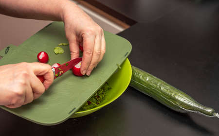 Close up view of female cutting radish for green salad. Healthy eating concept.の写真素材