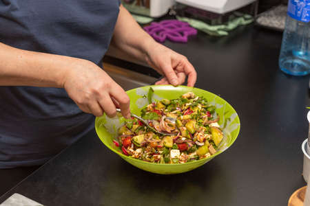 Close up view of woman making healthy green salad bowl.の写真素材