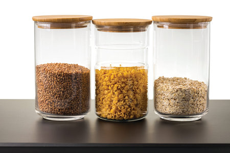 Close up view of glass jars with cereals and pasta on white background. Kitchen and healthy food...