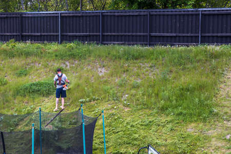 View of young man cutting grass with lawn mower. Sweden. Uppsala. 09/06/2021.のeditorial素材