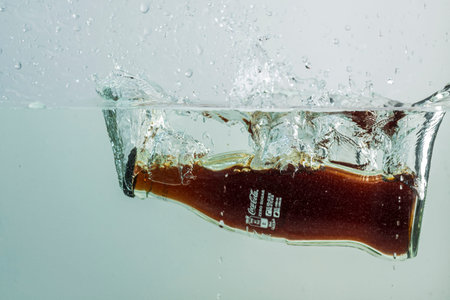 Close up view of Coca cola bottle falling in water. Sweden. Uppsala. 08.24.2021.