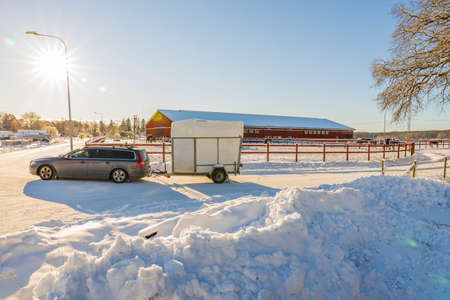 Beautiful winter landscape view. Ð¡ar with a horse trailer driving on road. Sweden.の写真素材