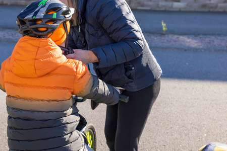 Woman helping child on bicycle with helmet.  Safety and health concept. Sweden.の写真素材