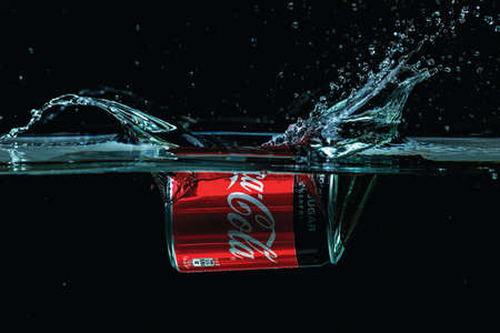 Close up view of can of Coca cola falling into water isolation on black background. Sweden. Uppsala. 10.24.2021.のeditorial素材