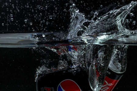 Close up view of can of coca cola, pepsi cola falling into water isolation on black background. Sweden. Uppsala. 06/11/2021.のeditorial素材