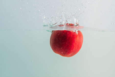 Close up view of red apples falling in water on background.の写真素材