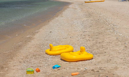Close up view of empty two yellow inflatable pools and toys for sand on beach. Greece.