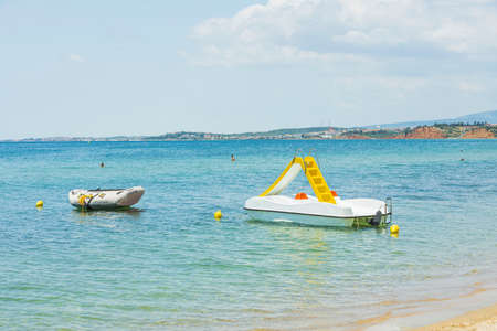 Close up view of water slide catamaran and rubber boat on sea coast on beautiful nature background. Greece. 09.10.2021.のeditorial素材