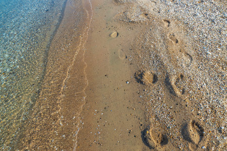 Beautiful view of footprints on sand along water on sunny summer day. Greece.の写真素材
