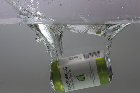 View of can of pear sider falling into water isolation on background. Sweden. Uppsala. 09/01/2022.