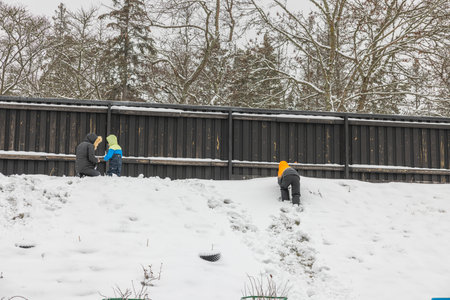 Beautiful view of woman and two children playing on snowy on snowy winter day. Sweden.