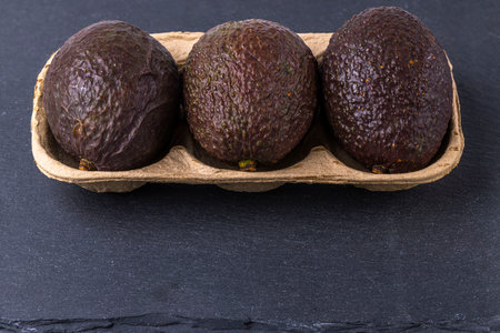 Close up view of avocado package isolated on a black rock cutting board.の写真素材