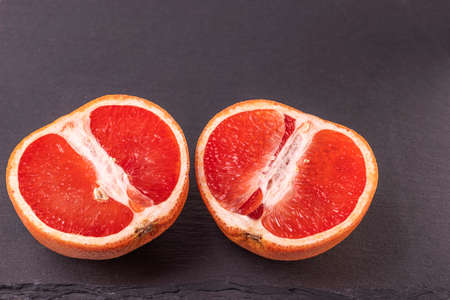 Close up view of ripe cut into two grapefruit isolated on cutting board.の写真素材