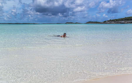 Beautiful view of man floating in Atlantic ocean on sandbar with white sand at low tide in Bahamas islands.の写真素材