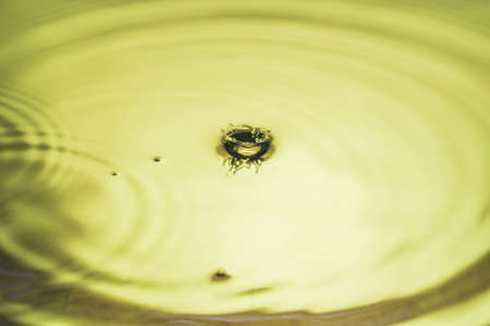 Beautiful view of drops making circles on yellow water surface isolated on background.の写真素材