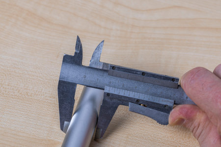 Close up view of hands man measuring an aluminum pipe with an calipers isolated. Sweden.