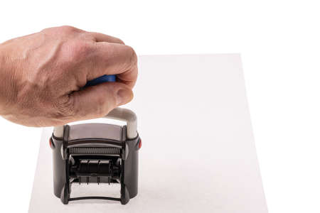Close up view of hand holding stamp on white paper background.の写真素材