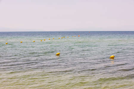 View of fenced area with buoys of sea coast of Mediterranean sea beach for safe swimming. Greece.の写真素材