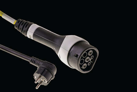 Close up view of electric vehicle cable charging for outdoor use with 16 A plug isolated on black background.の写真素材