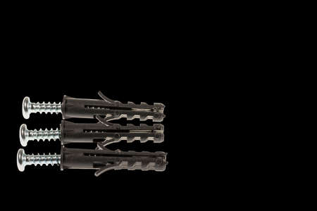 Close up view of screws screwed into black plastic screw caps isolated on black background.の写真素材