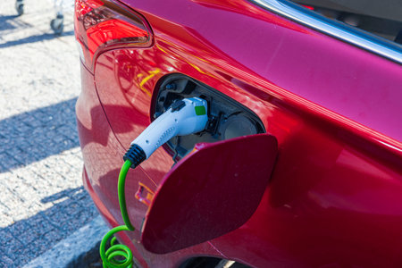 Close up view of connected charging cable to red car from an electric vehicle charging station. Sweden.の写真素材