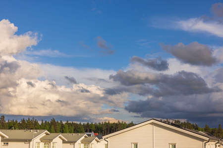 Beautiful blue sky landscape with thunder clouds over roofs of village houses. Sweden.の写真素材